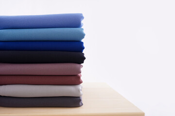 pile of cloth of various colors on a wooden table, photo stack of colorful cotton cloth isolated on white background.