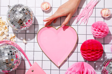 Disco balls, female hand and decorative heart on light background, top view