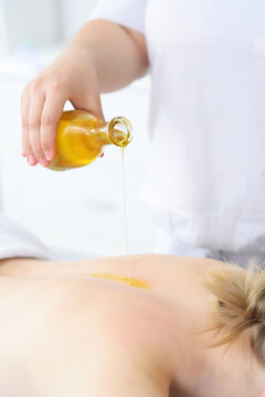 masseur pours massage oil close-up on the patient's back. Relaxing massage