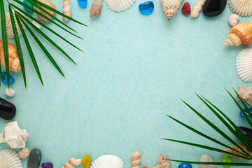 Summer sea background - Sea shells, colorful stones, and palm leaves on a cyan color background....