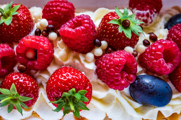 Close up shot of meringue roll Pavlova cake with cream and fresh berries: blueberries, raspberries, strawberries.