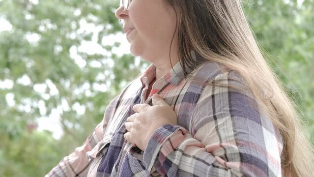 middle-aged caucasian woman in plaid shirt holds to heart, sudden chest pain, expression suffering, physical discomfort, Ischemic heart disease, Arterial hypertension, Myocarditis or Arrhythmia