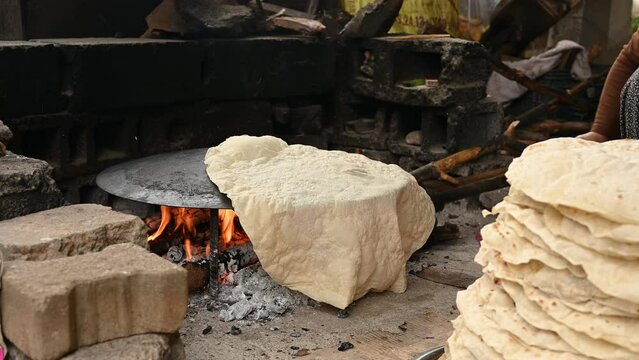 Turkish woman cooking traditional Turkish pastry called gozleme on special pan and open fire. 