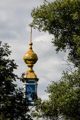 Golden domes of the Orthodox Church against the background of green trees