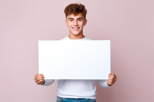 Happy young man holding blank white banner sign, isolated studio portrait.