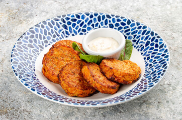 Pumpkin cutlets with white sauce in a decorative plate. Vegetarian dish. Isolated image on a white background.