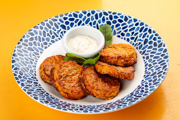 Pumpkin cutlets with white sauce in a decorative plate. Vegetarian dish. Isolated image on a white background.