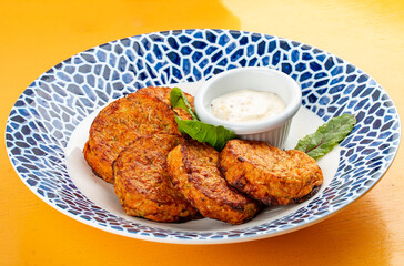 Pumpkin cutlets with white sauce in a decorative plate. Vegetarian dish. Isolated image on a white background.