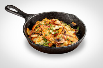 Fried potatoes with wild mushrooms and egg. In a cast iron skillet. Isolated image on white background.