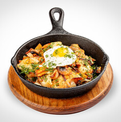 Fried potatoes with wild mushrooms and egg. In a cast iron skillet. Isolated image on white background.