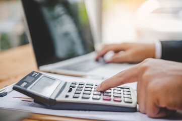 business person sitting at a desk at an office By using the calculator to work. Business Concept Analysis and Planning.