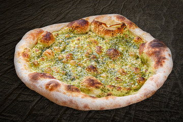 Italian focaccia bread with pesto, sesame seeds and parmesan. Neapolitan round pizza on wood background