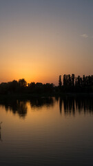 Fototapeta na wymiar Orange sunset near the calm water of the lake