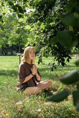 Woman meditates in nature outdoor.At ground level, a relaxed woman meditates and breathes while sitting in Lotus pose next to fragrant incense during a yoga class in the garden