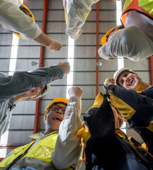 Celebrating Success: Hardhat construction workers raising their hands high, marking a victorious...