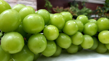 Muscat fresh green grapes stacked in heaps with blurry background.