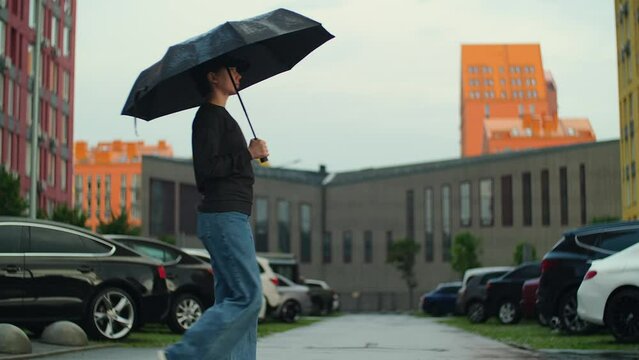 Woman with umbrella. Girl walking on pedestrian crossing under the rain. Rainy summer day with heavy rain, bad weather concept, city empty street. Slow motion shot