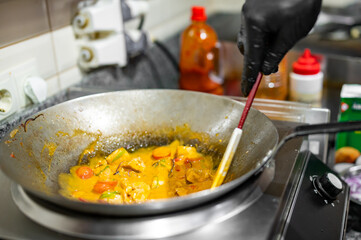 Professional chef cooking chicken curry food in wok pan on kitchen
