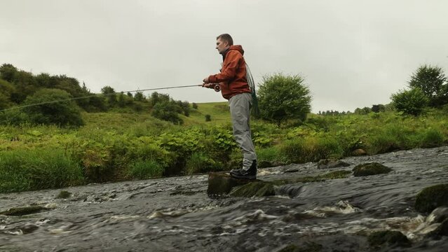 Low angle shot of a flyfisherman casting his rod and line into a river