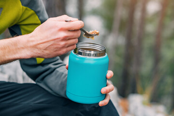 Morning ritual on the trail: A hiker prepares breakfast with a thermos and mug, blending cooking...