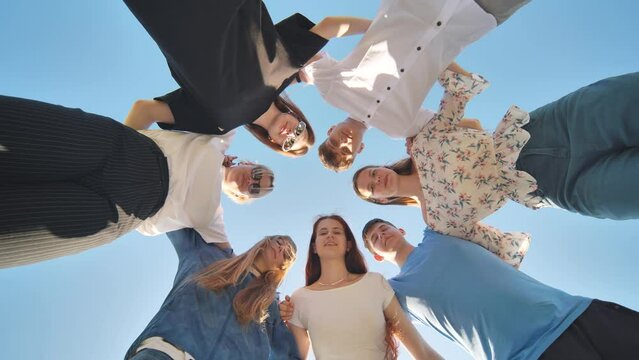 Seven young high school students amicably put their heads together and look down.