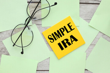 Photo of light yellow and green stickers, on a wooden board with the text SIMPLE IRA . and glasses