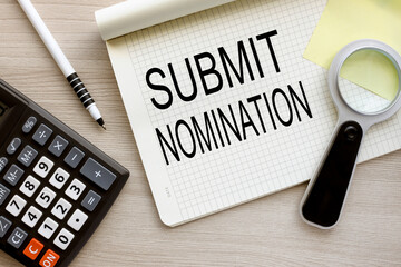 SUBMIT NOMINATION magnifying glass on the page. open notebook with text. wooden background.