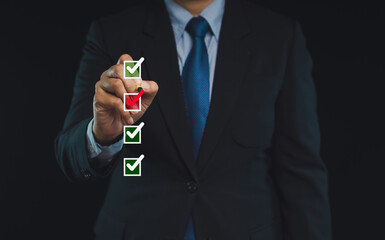 Businessman uses a pen to tick the correct sign in the checkbox for the quality document control...