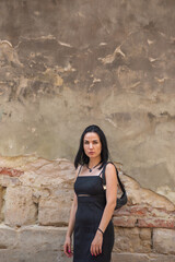 Beautiful young black hair woman walking on the summer street of old town in summer