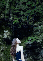 a beautiful woman on the background of a tropical forest with dripping drops of water, posing relaxed