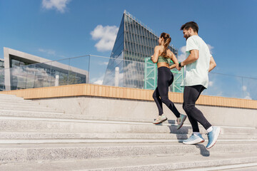 Runners partners training in sports clothes and running shoes.  Happy young people jogging together. Use a fitness watch and a cardio app. Athletes exercise for health.