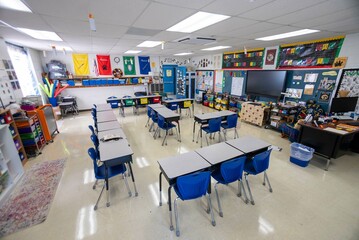 Wide angle view of empty elementary school classroom with interactive whiteboard no people and...