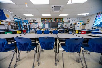 Wide angle view of empty elementary school classroom with interactive whiteboard no people and lights turned on.