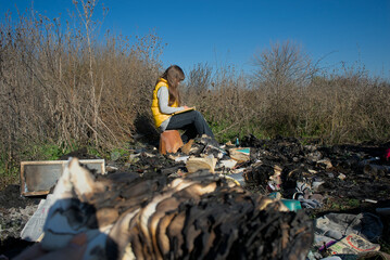 A child sits on the ashes among burnt books and reads a book preserved from the fire. Education...