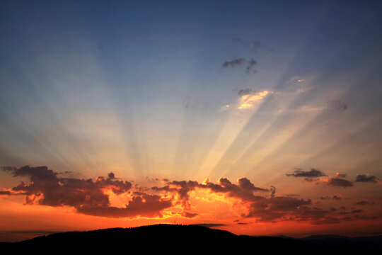 Abendrot mit beeindruckenden Sonnenstrahlen zwischen den Wolken über den Bergen