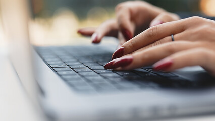 Woman's hands typing on the keyboard, close-up side view. Typing on a laptop keyboard. well-groomed woman's hands. business woman working on a computer