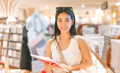 Portrait of beautiful young woman university student choosing book at bookstore shop