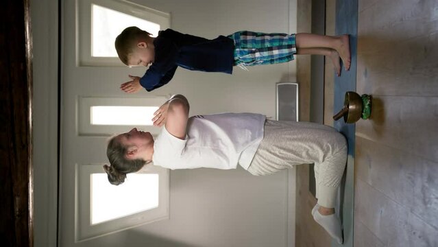 yoga and concentration, a young woman, together with her son, does the namaste exercise in a bright room, vertical format