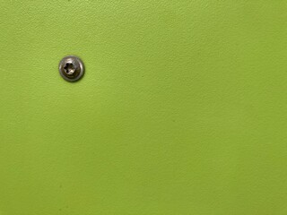 green plastic surface with a metal screw head