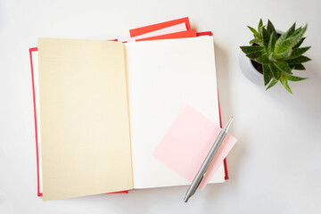 An open book with a red cover and stickers for notes near with potted plant are on the table. The theme is book day and knowledge day. Copy space.