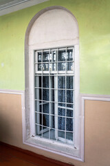 Old window with bars on the wall of a rural house