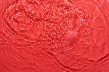 Water red surface abstract background. Waves and ripples texture of cosmetic aqua moisturizer with bubbles.