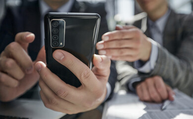 manager uses smartphone while sitting at table with colleague