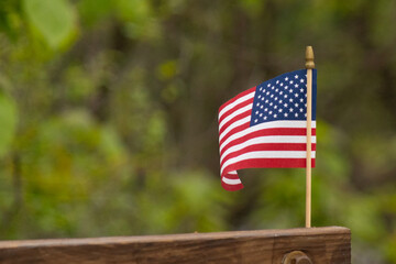 This is an image of a small American flag pinned to a wooden beam. This patriotic display looks...