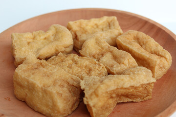 Fried tofu on wooden plate, on white background