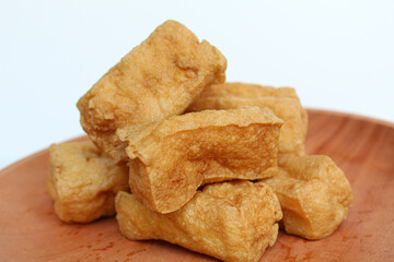 Fried tofu on wooden plate, on white background
