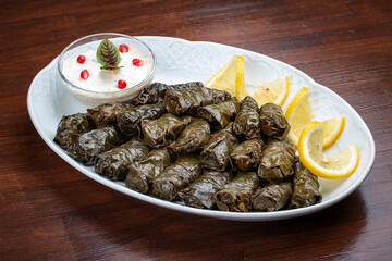 Dolma with lamb and white sauce. Grape leaves with minced meat. Oriental cuisine. Isolated on a dark background