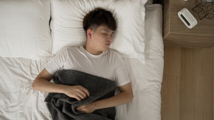 top angle view of an asian man tossing and turning in bed and nearly waking up from sleep in the...