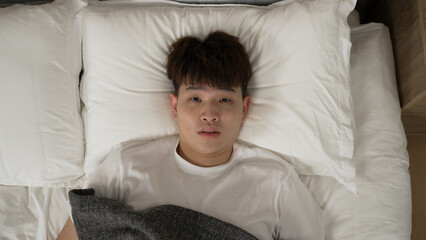 zoom in with view from above stressed Taiwanese guy haunted by nightmare is waking up and looking...