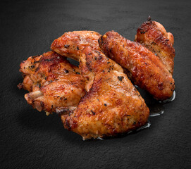 Grilled chicken wings on a dark stone background. BBQ menu